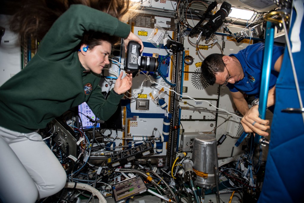 iss068e042187 (Jan. 26, 2023) --- Roscosmos cosmonaut Anna Kikina photographs NASA astronaut Frank Rubio, both Expedition 68 flight engineers, as he conducts orbital plumbing work aboard the International Space Station.