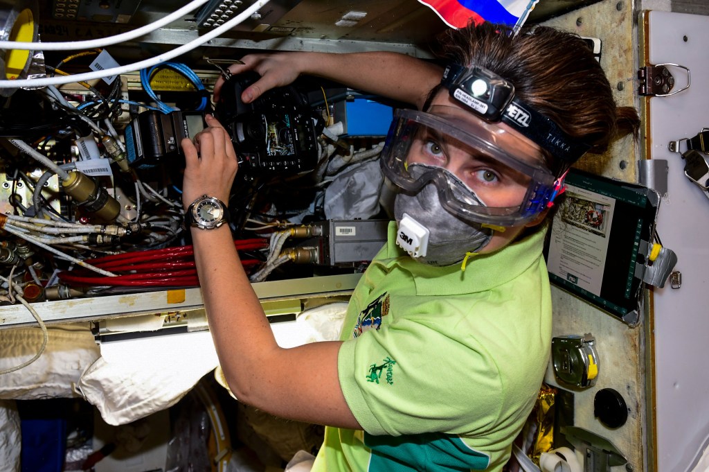 iss068e032401 (Dec. 22, 2023) --- Roscosmos cosmonaut and Expedition 68 Flight Engineer Anna Kikina conducts communications and electronics maintenance while wearing personal protective equipment aboard the International Space Station.