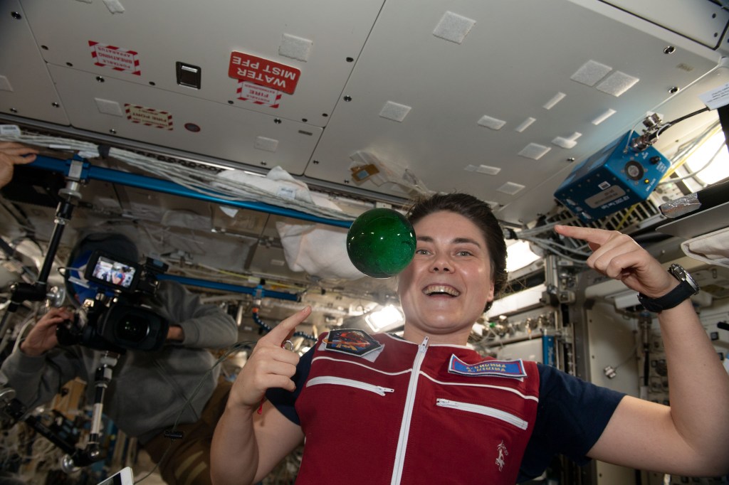 iss068e051617 (Feb. 12, 2023) --- Roscosmos cosmonaut and Expedition 68 Flight Engineer Anna Kikina plays with a sphere of water flying in microgravity that has been dyed with green food coloring and is bubbling due to an antacid that was placed inside.