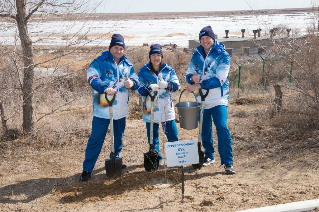 At the Cosmonaut Hotel crew quarters in Baikonur, Kazakhstan, Expedition 59 crew members Alexey Ovchinin of Roscosmos (left), Christina Koch of NASA (center) and Nick Hague of NASA (right) pose for pictures March 7 after Koch planted a tree in her name in traditional pre-launch activities. They will launch March 14, U.S. time, on the Soyuz MS-12 spacecraft from the Baikonur Cosmodrome for a six-and-a-half month mission on the International Space Station.