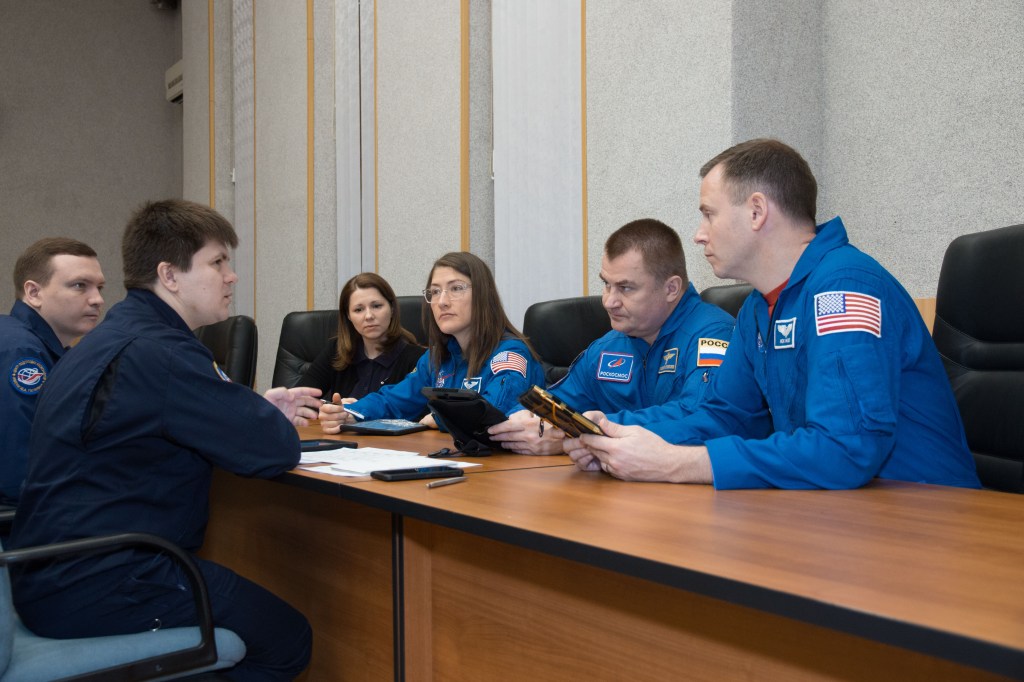 At their Cosmonaut Hotel crew quarters in Baikonur, Kazakhstan, Expedition 59 crew members Christina Koch of NASA (second from the left), Alexey Ovchinin of Roscosmos (second from the right) and Nick Hague of NASA (right) review flight plan activities March 7 with instructors as they prepare for launch. They will launch March 14, U.S. time, on the Soyuz MS-12 spacecraft from the Baikonur Cosmodrome for a six-and-a-half month mission on the International Space Station.