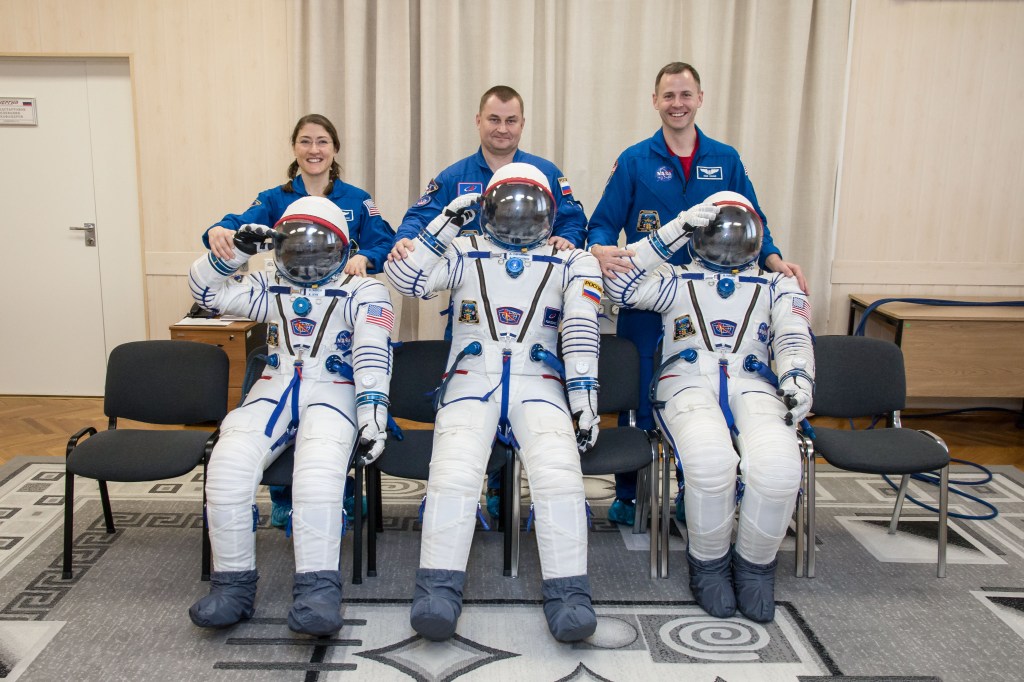 At the Baikonur Cosmodrome in Kazakhstan Expedition 59 crew members Christina Koch of NASA (left), Alexey Ovchinin of Roscosmos (center) and Nick Hague of NASA (right) share a playful moment with their Sokol launch and entry suits Feb. 27 after completing the first of two Soyuz spacecraft fit checks during pre-launch training. They will launch March 14, U.S. time, on the Soyuz MS-12 spacecraft from the Baikonur Cosmodrome in Kazakhstan for a six-and-a-half month mission on the International Space Station.