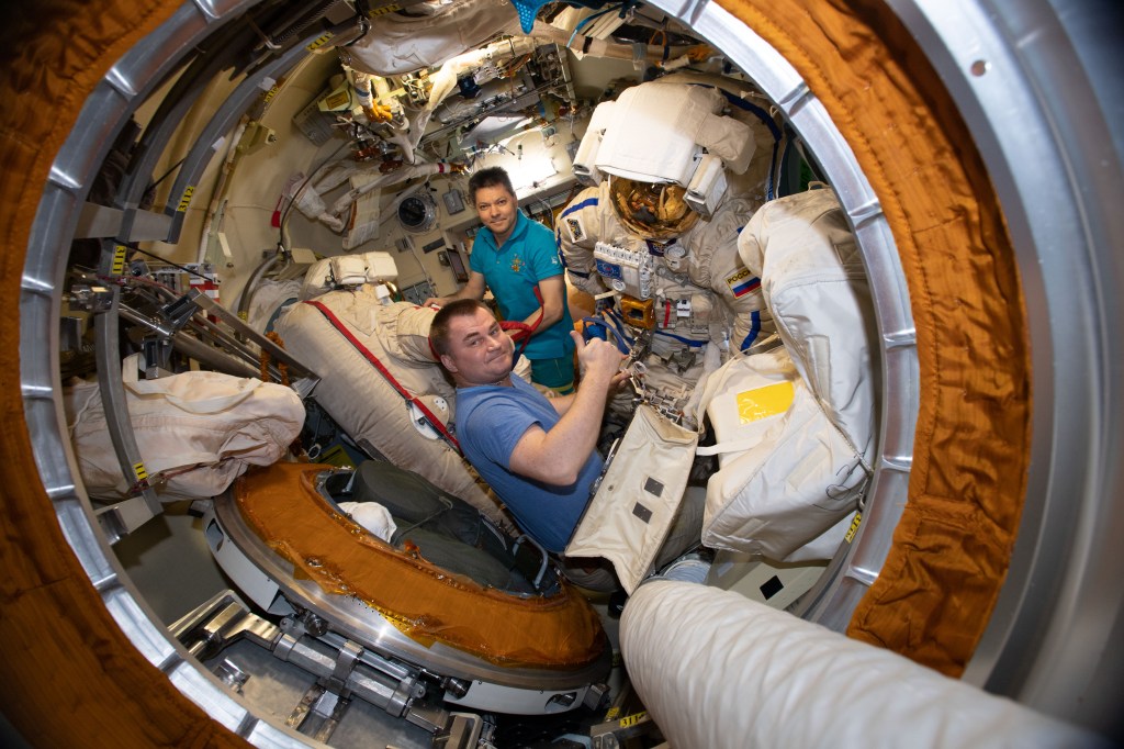 Expedition 59 Flight Engineer Alexey Ovchinin (foreground) and Commander Oleg Kononenko ready a pair of Russian Orlan spacesuits inside the Pirs docking compartment's airlock. Ovchinin and Kononenko are due to conduct the fourth spacewalk of 2019 for space station maintenance on May 29.