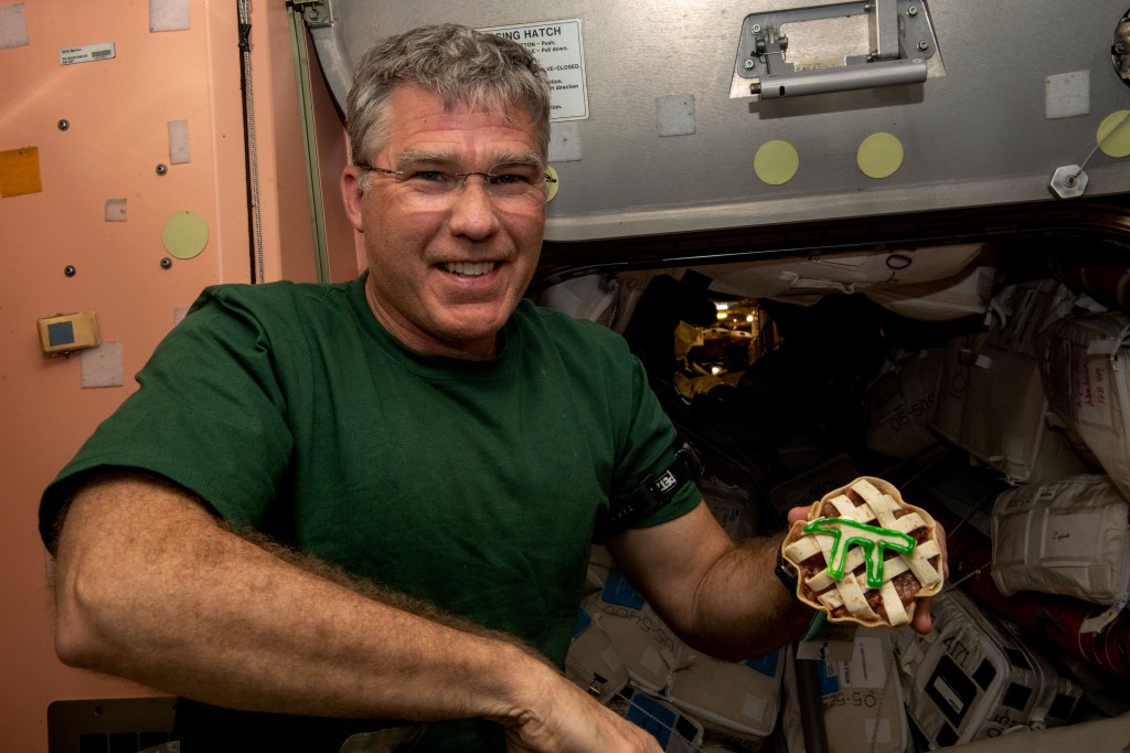 iss068e075336 (March 13, 2021) --- NASA astronaut and Expedition 68 Flight Engineer Stephen Bowen is pictured with a small pie in commemoration of Pi Day aboard the International Space Station.