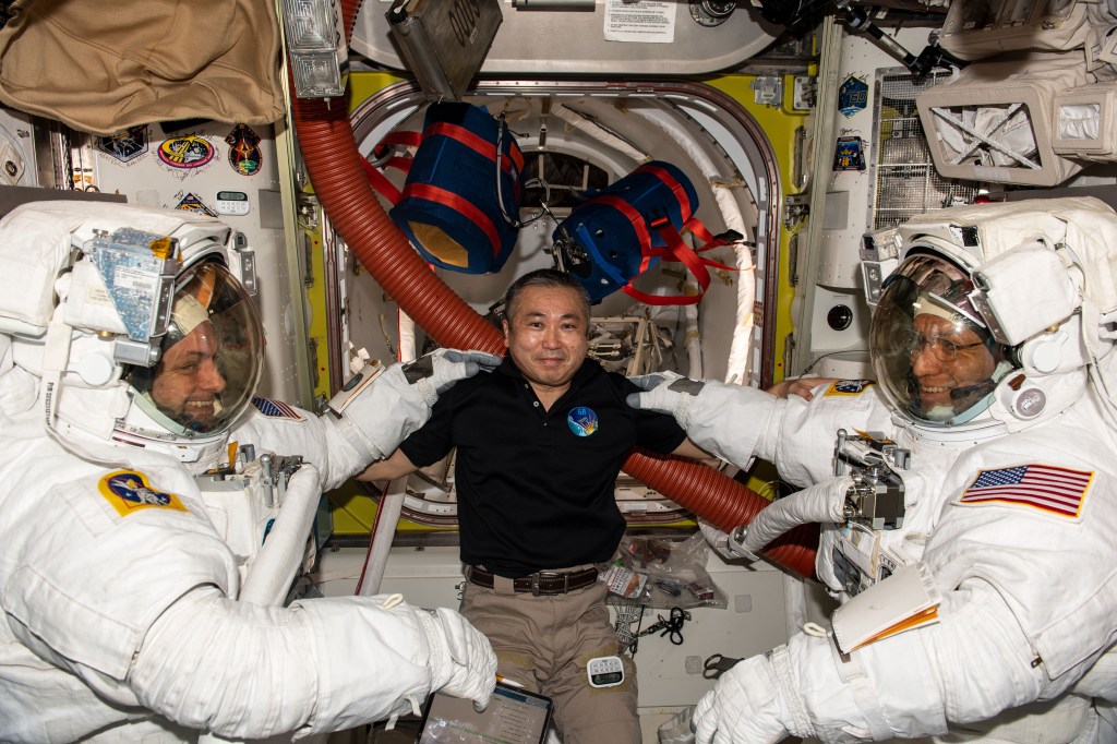 iss068e031347 (Dec. 21, 2022) --- Expedition 68 Flight Engineer Koichi Wakata (center) of the Japan Aerospace Exploration Agency (JAXA) poses with NASA spacewalkers Josh Cassada (left) and Frank Rubio (right) who were suited up and ready to begin a spacewalk to install a roll-out solar array on the International Space Station's Port-4 truss segment. The spacewalk was ultimately postponed for 24 hours so that the orbiting lab’s ISS Progress 81 cargo craft could fire its engines to maneuver the station and avoid an approaching piece of rocket debris.