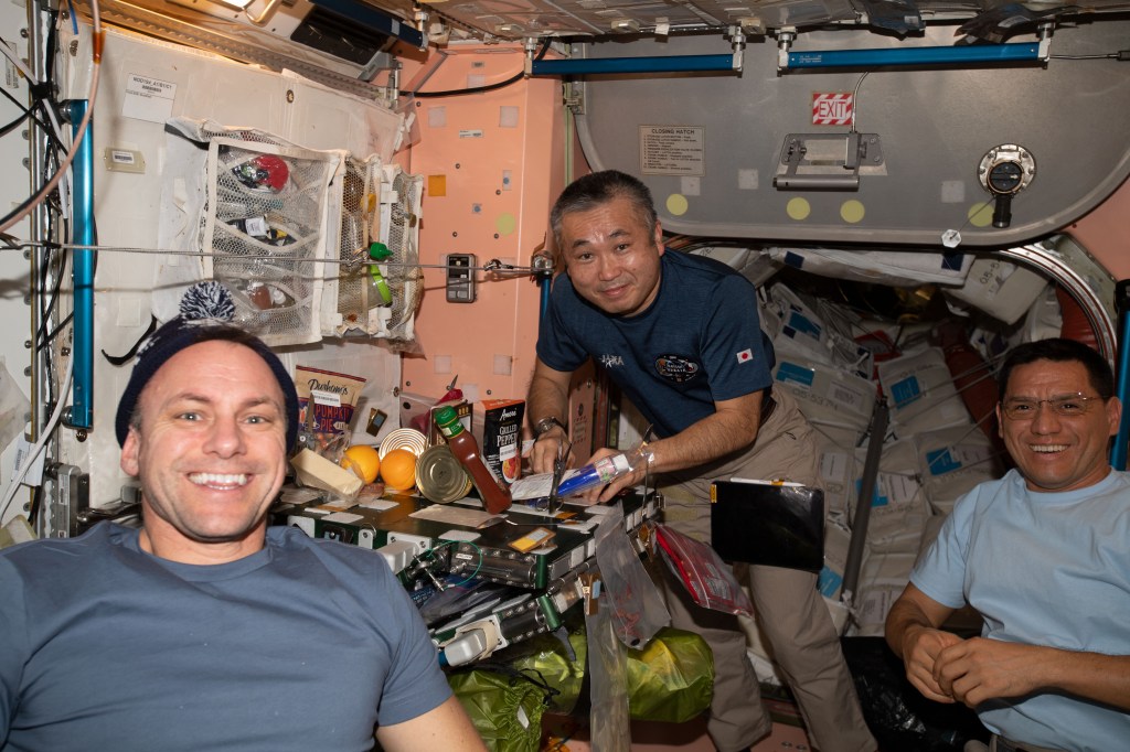 iss068e032600 (Dec. 24, 2022) --- Expedition 68 Flight Engineers (from left) Josh Cassada of NASA, Koichi Wakata of the Japan Aerospace Exploration Agency (JAXA), and Frank Rubio of NASA, pose for a photograph while sharing a meal on Christmas Eve inside the International Space Station's Unity module.