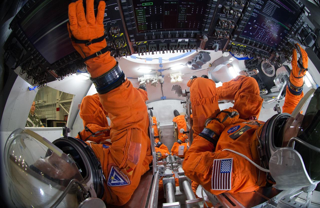 Spacesuit engineers demonstrate how four crew members would be arranged for launch inside the Orion spacecraft, using a mockup of the vehicle at Johnson Space Center in Houston on Oct. 24, 2014.