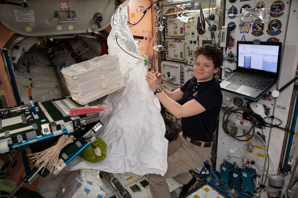 NASA astronaut Anne McClain assembles a hygiene cover that will cover a rack bay inside the Permanent Multipurpose Module.