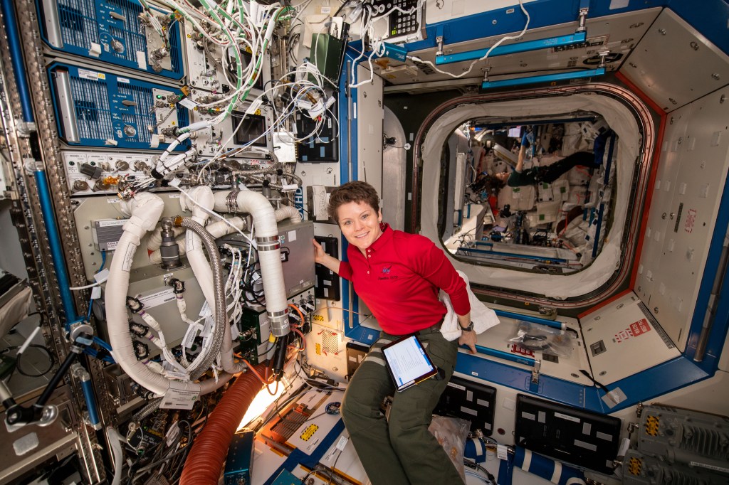 NASA astronaut and Expedition 59 Flight Engineer Anne McClain is photographed in the Destiny laboratory module onboard the International Space Station during the installation of the Thermal Amine Scrubber. The Thermal Amine Scrubber tests a method to remove carbon dioxide from air aboard the station, using actively heated and cooled amine beds.