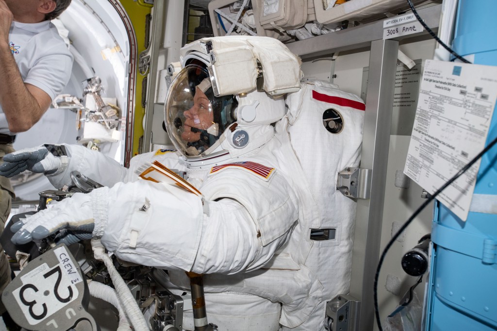 NASA astronaut Anne McClain is suited up in the U.S. Quest airlock preparing to begin her first career spacewalk with fellow NASA astronaut Nick Hague (out of frame). Hague and McClain would work outside in the vacuum of space for six hours and 39 minutes to upgrade the International Space Station's power storage capacity.