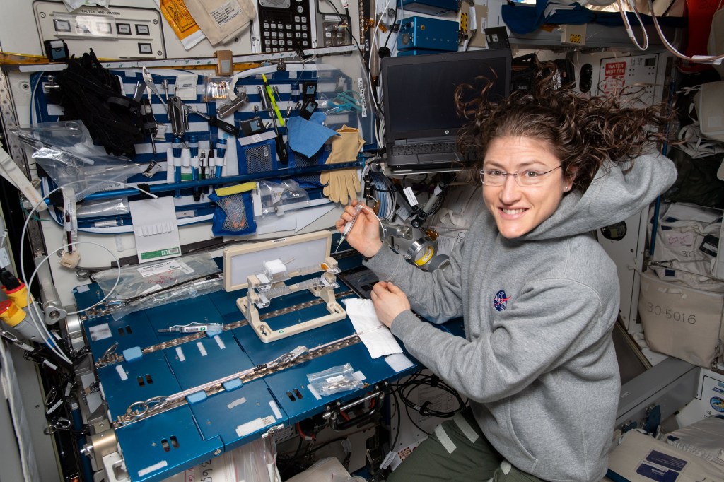 NASA astronaut Christina Koch checks out hardware for the Capillary Structures experiment. The investigation studies a new method of using structures of specific shapes to manage fluid and gas mixtures for more reliable life support systems on future space missions.