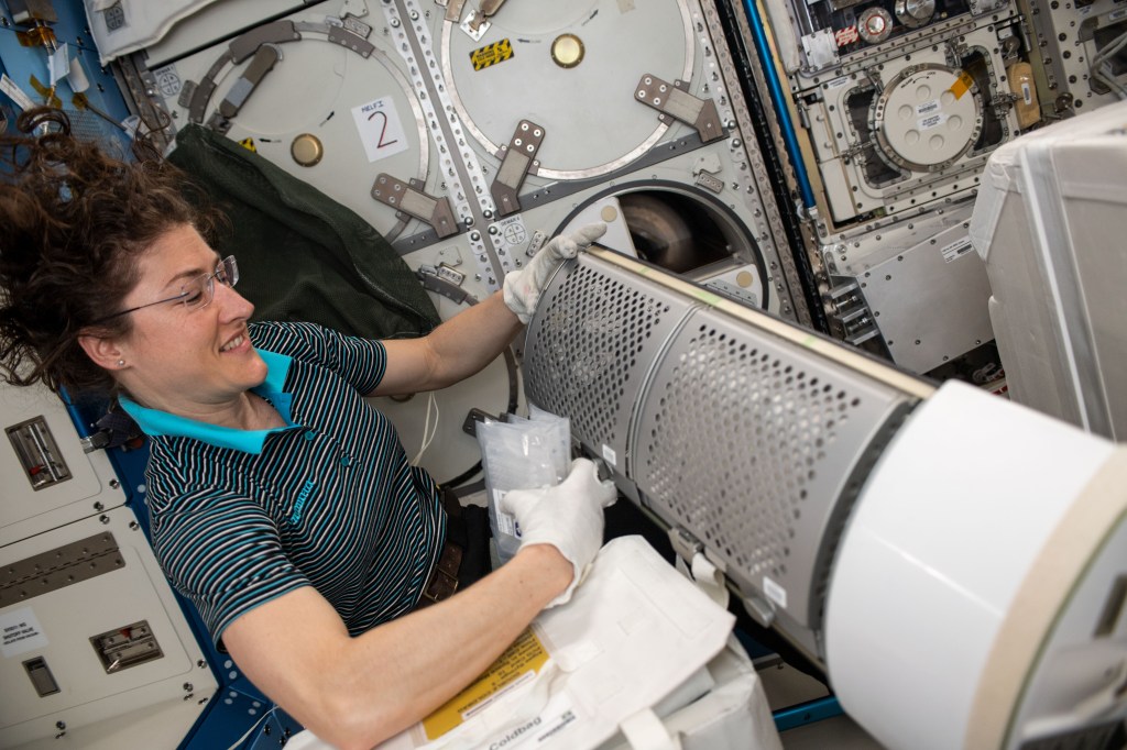 NASA astronaut Christina Koch stows frozen science samples delivered inside the SpaceX Dragon resupply ship into a science freezer aboard the International Space Station.
