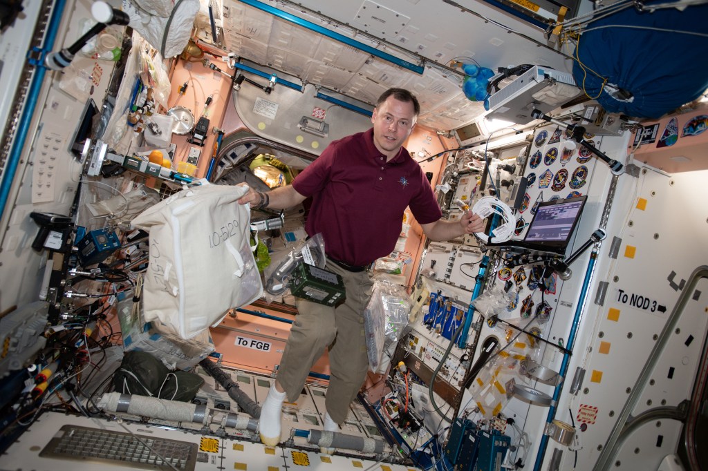 NASA astronaut Nick Hague works inside the Unity module setting up computer hardware aboard the International Space Station.