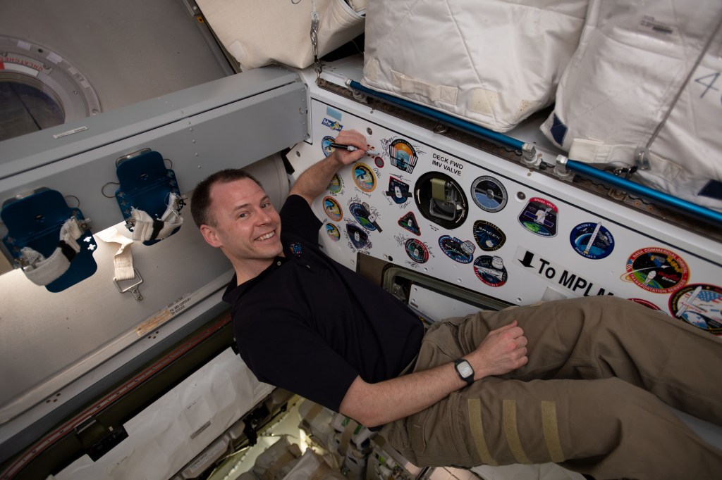 NASA astronaut Nick Hague signs the inside of the vestibule between the SpaceX Dragon cargo craft and the Harmony module. The hatch to Dragon was later closed and the resupply ship detached from Harmony before it was released from the grips of the Canadarm2 robotic arm. Dragon spent nearly a month attached to the International Space Station.