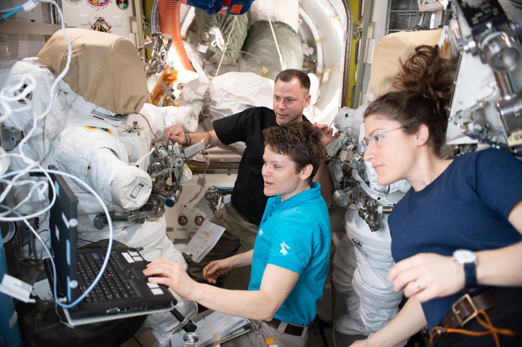 NASA astronauts Nick Hague, Anne McClain and Christina Koch (right) work on U.S. spacesuit maintenance in the Quest airlock of the International Space Station.