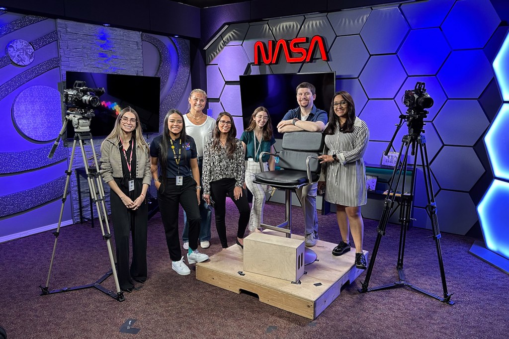 A group of seven interns posing in a NASA tv studio.