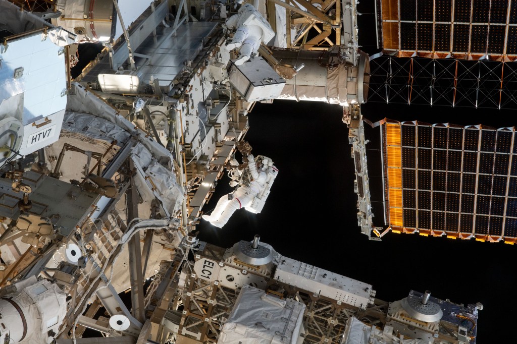 Spacewalkers and NASA astronauts Christina Koch (center top) and Nick Hague (suit with red stripe on legs) swap batteries and install adapter plates on the International Space Station's Port-4 truss structure. The duo worked outside in the vacuum of space for six hours and 45 minutes to continue upgrading the orbital complex's power storage capacity.