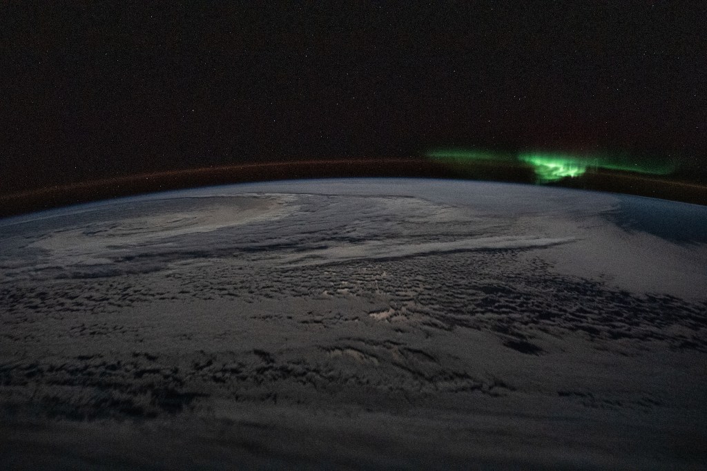 The atmospheric glow and a wispy aurora australis, also known as the "southern lights," frame a cloud-covered Earth as the International Space Station orbited 254 miles above the Indian Ocean due east of the territory of French Southern and Antarctic Lands.