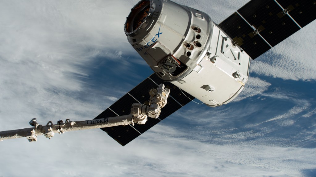 The Canadarm2 robotic arm, commanded by astronaut David Saint-Jacques, reaches out to grapple the SpaceX Dragon cargo craft at its capture point 10 meters from the International Space Station. Astronaut Nick Hague backed up Saint-Jacques and monitored systems.