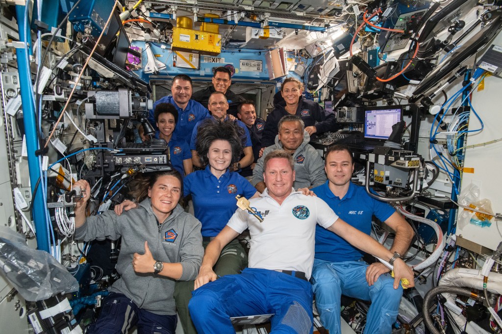 iss068e016856 (Oct. 12, 2022) --- The eleven Expedition 68 crew members aboard the International Space Station pose for a portrait. In the front row from left, are cosmonauts Anna Kikina, Sergey Prokopyev, and Dmitri Petelin. In the next row, are astronauts Samantha Cristoforetti of ESA (European Space Agency) and Koichi Wakata of the Japan Aerospace Exploration Agency (JAXA). In the back, are NASA astronauts Jessica Watkins, Kjell Lindgren, Bob Hines, Frank Rubio, Josh Cassada, and Nicole Mann. A symbolic key, representing the traditional change of command ceremony, that Cristoforetti earlier handed over to Prokopyev floats in the center of the frame as he begins his spaceflight as Expedition 68 Commander.