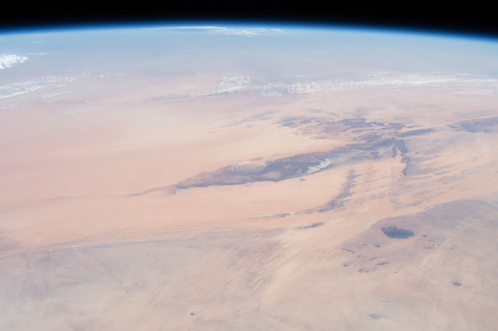 This oblique view from 255 miles above northwest Africa, looking from north to south, shows the "Eye of Sahara" in Mauritania. The circular geologic feature, also known as the Richat Structure, is thought to be caused by an uplifted dome—geologists would classify it as a domed anticline—that has been eroded to expose the originally flat rock layers.