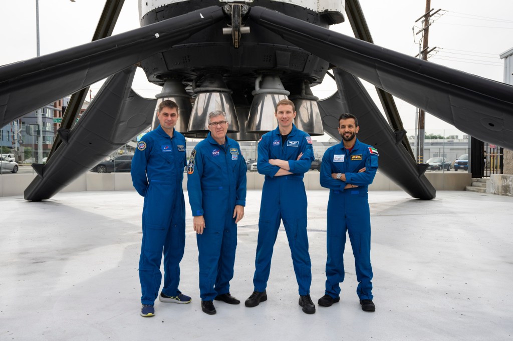jsc2023e002308 (Jan. 13, 2023) --- The four SpaceX Crew-6 members pose for a portrait underneath a Falcon 9 rocket booster at the company's headquarters in Hawthorne, California. From left, are Mission Specialist Andrey Fedyaev of Roscosmos; Commander Stephen Bowen and Pilot Warren "Woody" Hoburg, both from NASA; and Mission Specialist Sultan Alneyadi from the Mohammed bin Rashid Space Centre. Credit: SpaceX