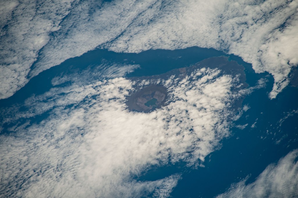 iss068e025397 (Nov. 28, 2022) --- The peak of La Cumbre Volcano on Ecuador's Fernandina Island, part of the Galapagos Islands, is surrounded by clouds in this photograph from the International Space Station as it orbited 261 miles above the Pacific Ocean.