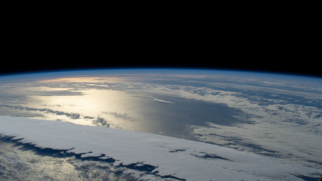 iss068e036653 (Jan. 1, 2022) --- The sun's glint beams off a partly cloudy Pacific Ocean in this photograph from the International Space Station as it orbited 260 miles above and northwest of Midway Atoll.