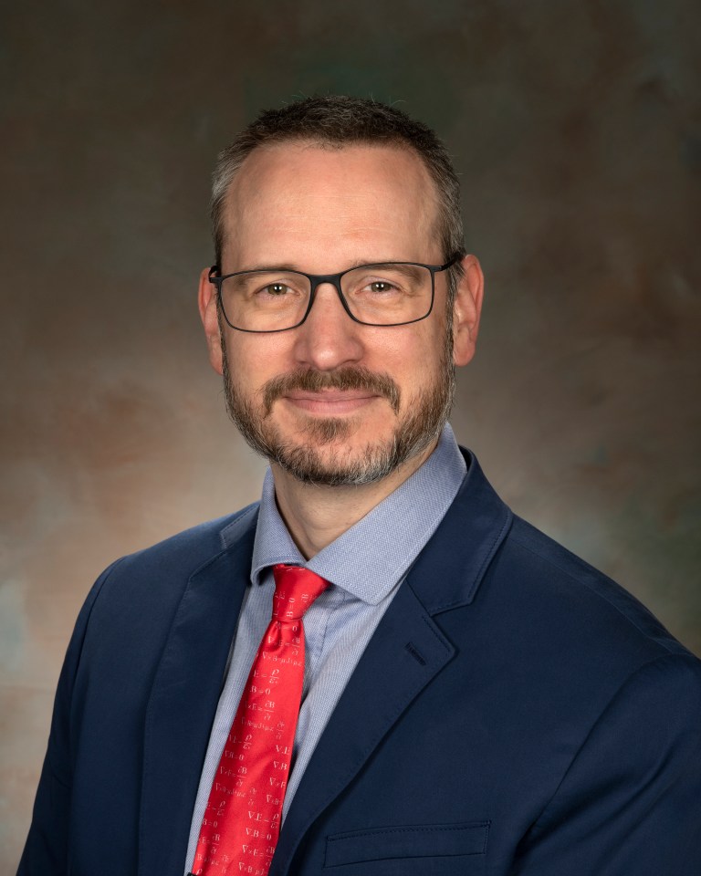 Portrait of a man in a suit and red tied.