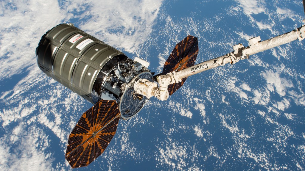 Northrop Grumman's Cygnus space freighter with its prominent cymbal-shaped UltraFlex solar arrays is pictured in the grips of the Canadarm2 robotic arm after it was captured by Expedition 57 Flight Engineer Serena Auñón-Chancellor and ESA (European Space Agency) astronaut Alexander Gerst.