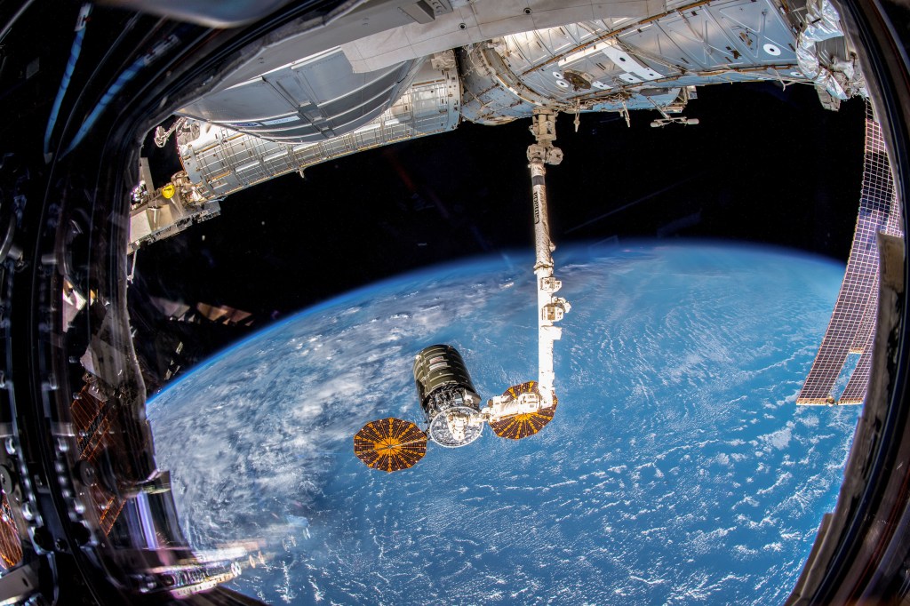 Northrop Grumman's Cygnus space freighter with its prominent cymbal-shaped UltraFlex solar arrays is pictured in the grips of the Canadarm2 robotic arm after it was captured by Expedition 57 Flight Engineer Serena Auñón-Chancellor and ESA (European Space Agency) astronaut Alexander Gerst.