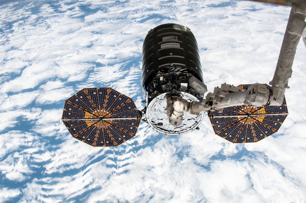 Northrop Grumman's Cygnus space freighter with its prominent cymbal-shaped UltraFlex solar arrays is pictured in the grips of the Canadarm2 robotic arm after it was captured by Expedition 57 Flight Engineer Serena Auñón-Chancellor and ESA (European Space Agency) astronaut Alexander Gerst.