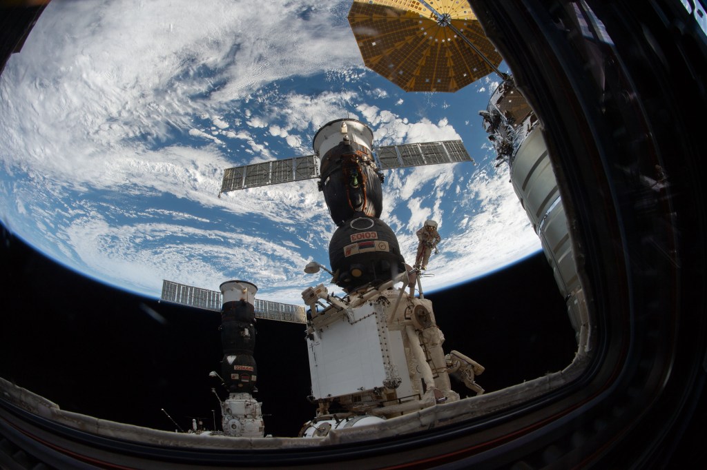 An Expedition 57 crew member inside the cupola photographed Russian spacewalker Oleg Kononenko (suit with red stripes) attached to the Strela boom outside the International Space Station about 250 miles above Earth to inspect the Soyuz MS-09 spacecraft. During the spacewalk, he and fellow spacewalker Sergey Prokopyev (towards bottom right in the suit with blue stripes) examined the external hull of the Soyuz crew ship docked to the Rassvet module. The area corresponded with the location of a small hole inside the Soyuz habitation module that was found in August and caused a decrease in the space station’s pressure. The hole was fixed internally with a sealant within hours of its detection. During the spacewalk, Kononenko and Prokopyev collected samples of some of the sealant that extruded through hole to the outer hull before heading back inside the Pirs docking compartment and closing the hatch completing a seven-hour, 45-minute spacewalk.