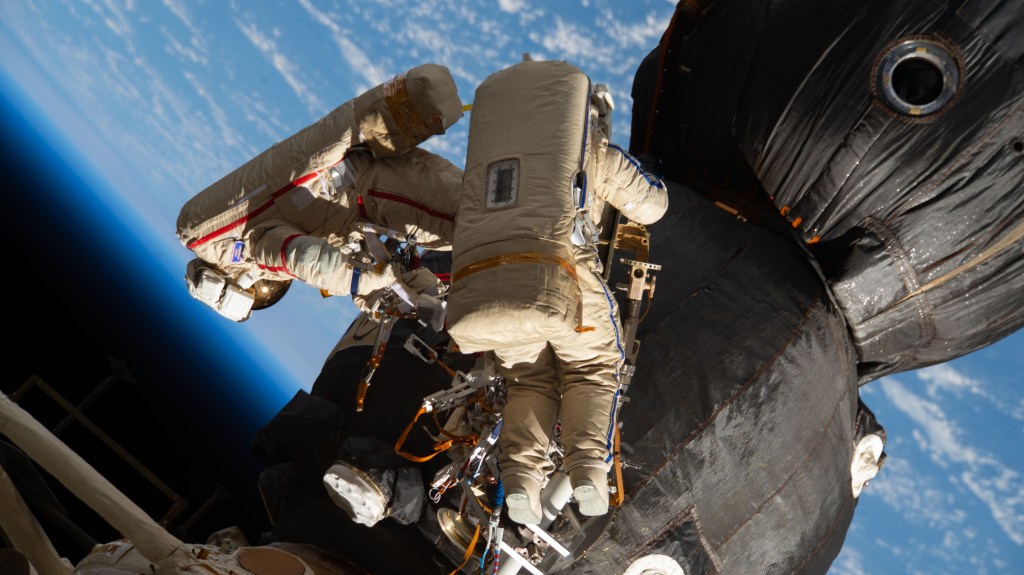 Russian spacewalkers Oleg Kononenko (suit with red stripes) and Sergey Prokopyev (suit with blue stripes) work outside the International Space Station over 250 miles above Earth to inspect the Soyuz MS-09 spacecraft. During the spacewalk, the two examined the external hull of the Soyuz crew ship docked to the Rassvet module, took images and applied a thermal blanket. They also retrieved science experiments before heading back inside the Pirs docking compartment and closing the hatch completing a seven-hour, 45-minute spacewalk.the duo examined the external hull of the Soyuz crew ship docked to the Rassvet module. The area corresponded with the location of a small hole inside the Soyuz habitation module that was found in August and caused a decrease in the space station’s pressure. The hole was fixed internally with a sealant within hours of its detection. During the spacewalk, Kononenko and Prokopyev collected samples of some of the sealant that extruded through hole to the outer hull before heading back inside the Pirs docking compartment and closing the hatch completing a seven-hour, 45-minute spacewalk.