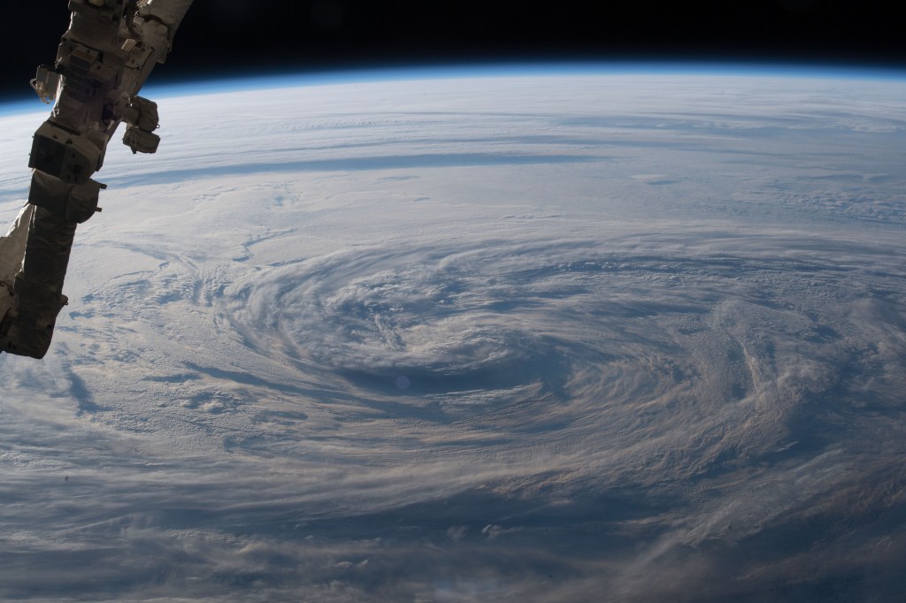 A portion of the Canadarm2 robotic arm (left) and stormy clouds are seen in the north Pacific Ocean as the International Space Station orbited off the eastern coast of Russia.