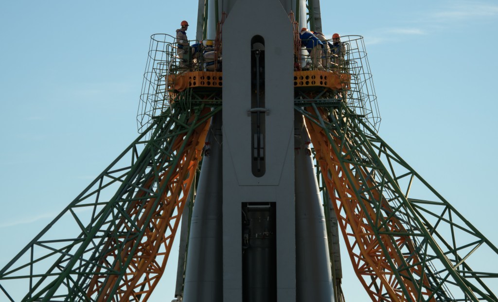 Workers are seen around the Soyuz rocket after it was raised into a vertical position on the launch pad, Tuesday, Oct. 9, 2018 at the Baikonur Cosmodrome in Kazakhstan. Expedition 57 crewmembers Nick Hague of NASA and Alexey Ovchinin of Roscosmos are scheduled to launch on October 11 and will spend the next six months living and working aboard the International Space Station.