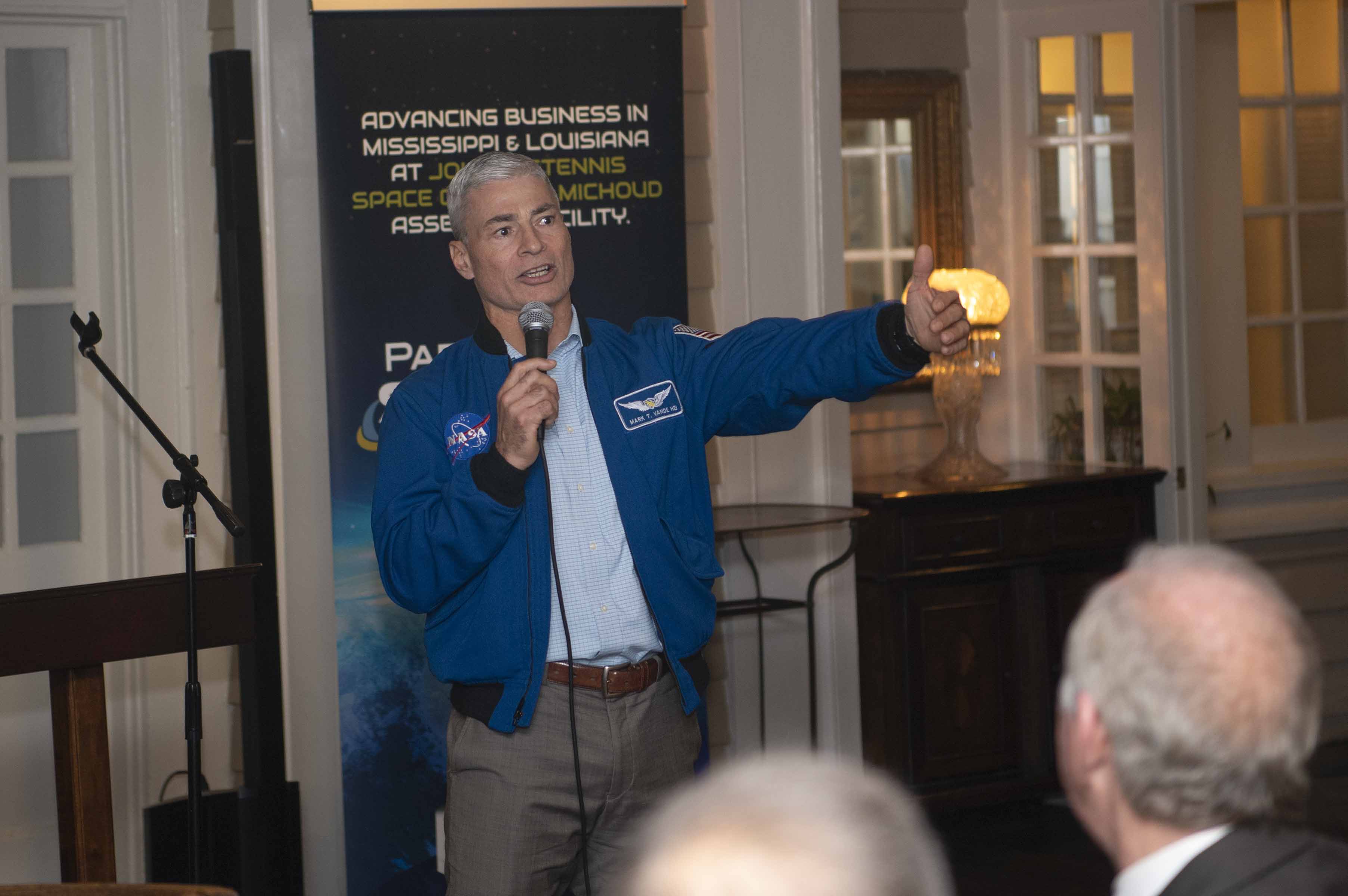 NASA astronaut Mark Vande Hei, wearing a blue bomber jacket, speaks to reception attendees