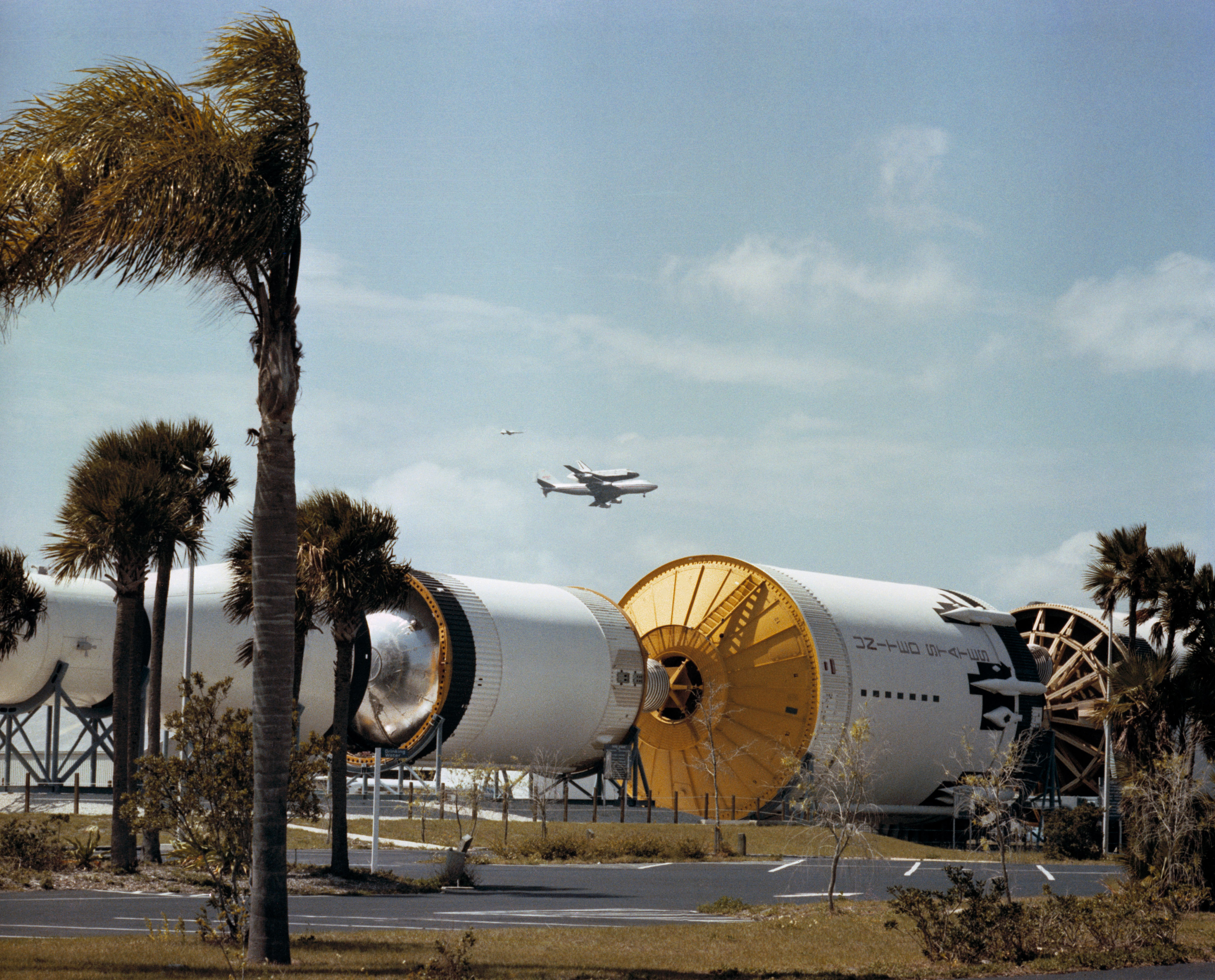 Space shuttle Columbia atop its Shuttle Carrier Aircraft (SCA) flies over the Saturn V display at NASA’s Kennedy Space Center (KSC) in Florida