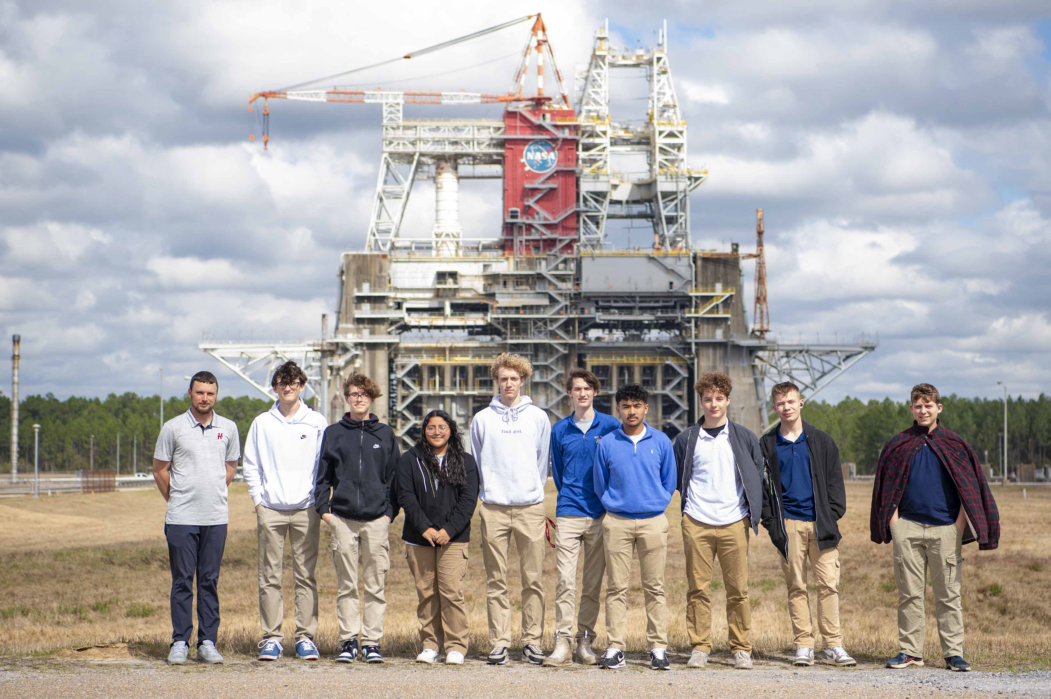 a row of high school students stand in the forefront with the Thad Cochran Test Stand in the background