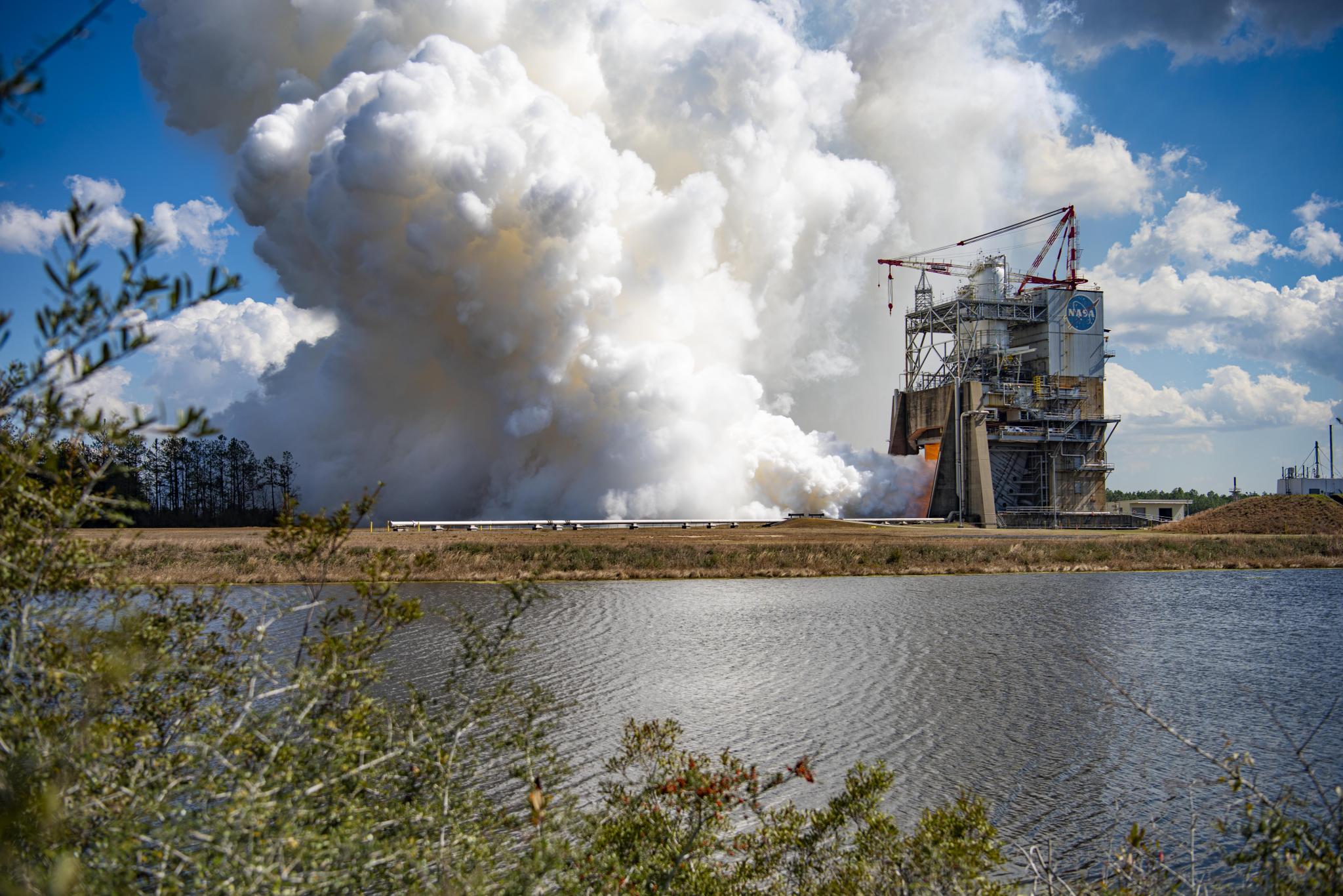 vapor clouds erupt from a RS-25 hot fire from across the water