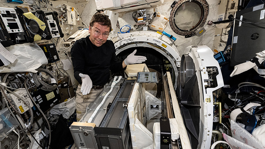 Astronaut MIke Barratt installs a small satellite orbital deployer inside the Kibo laboratory module's airlock.