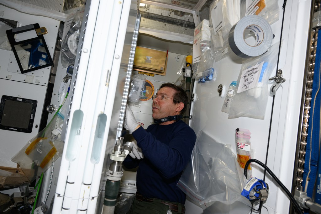 Expedition 71 Flight Engineer and NASA astronaut Mike Barratt works on orbital plumbing duties inside the Waste and Hygiene Compartment, the International Space Station's bathroom located aboard the Tranquility module.