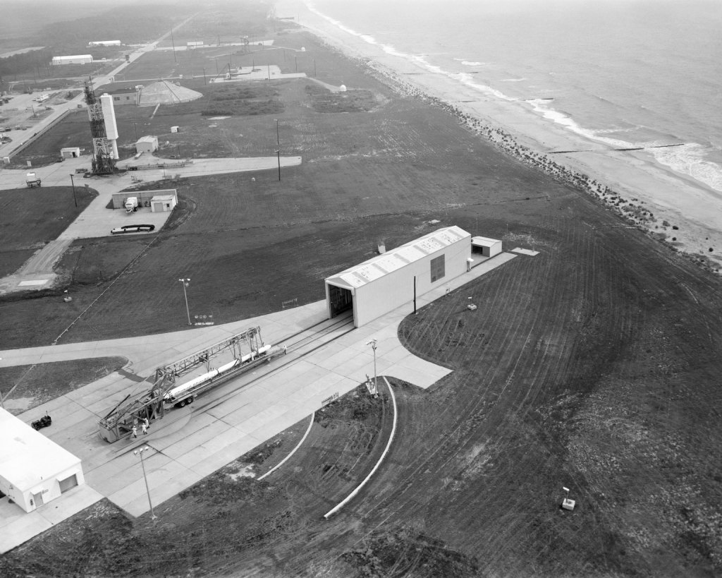 1965 Black and white image of a sounding rocket launcher and vertical rocket launcher with support buildings and roads on Wallops Island, Virginia.