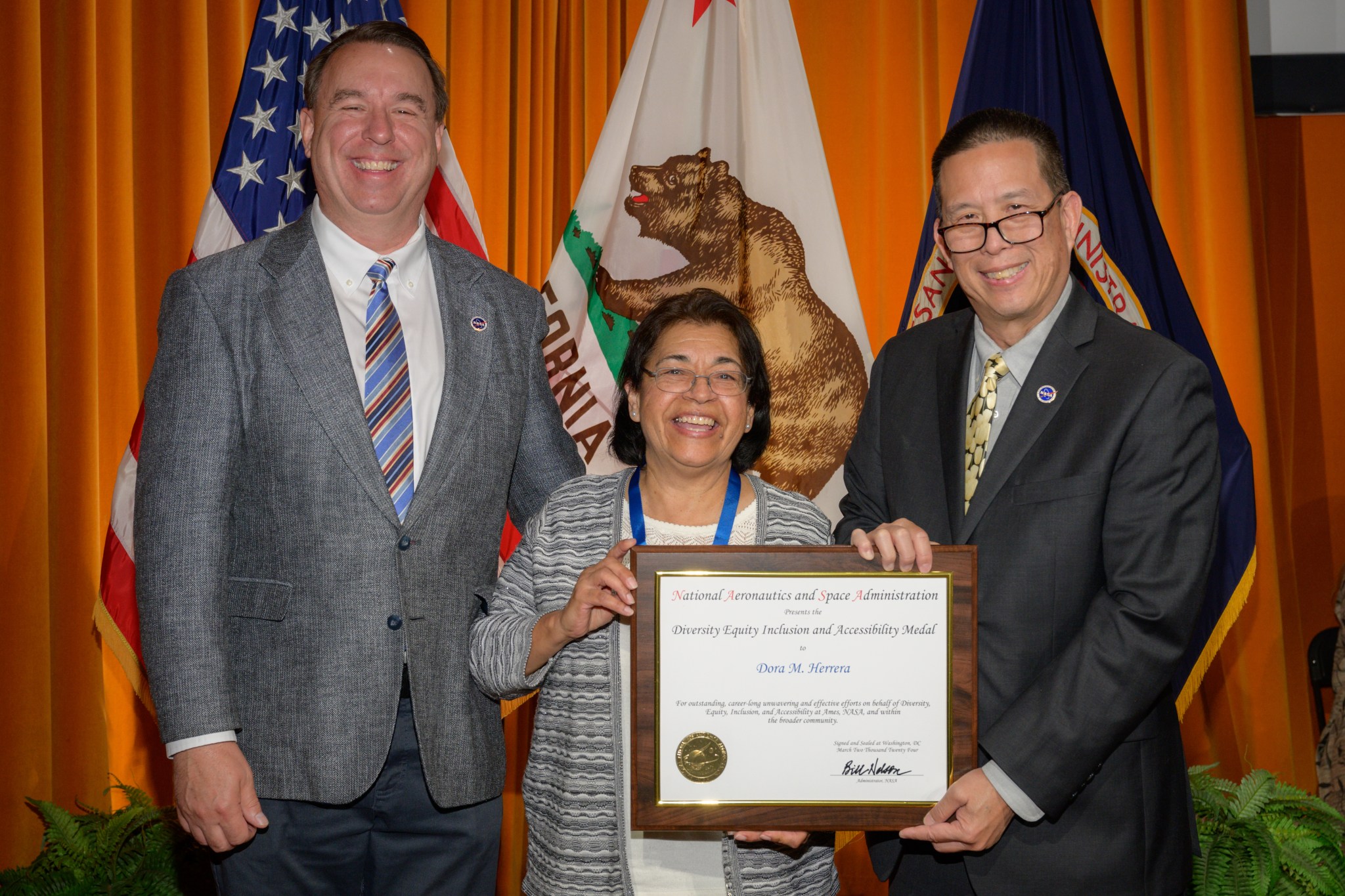 2023 Diversity, Equity, Inclusion and Accessibility Medal presented to Dora Herrera, center, by Center Director Eugene Tu, right, and Deputy Center Director David Korsmeyer, left, in the N201 Auditorium