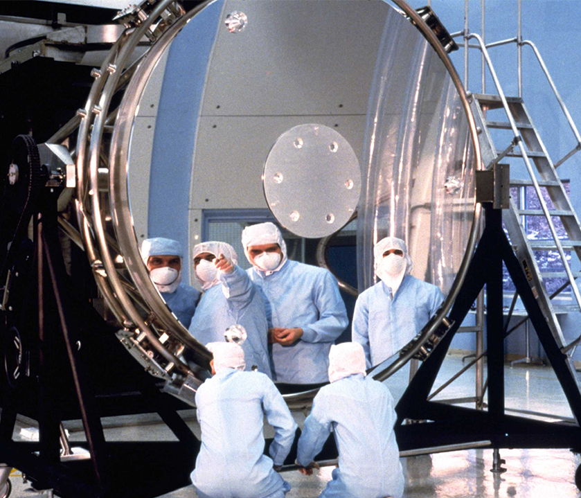 Workers inspect the Hubble Space Telescope's 94-inch diameter primary mirror prior to assembly