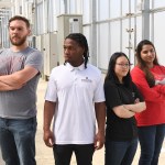 The four Deep Space Food Challenge Simunauts stand next to each other, each looking in different directions away from the camera. From left to right: Charlie Frick, Fuanyi Fobellah, Sakura Sugiyama, and Mehr Un Nisa.