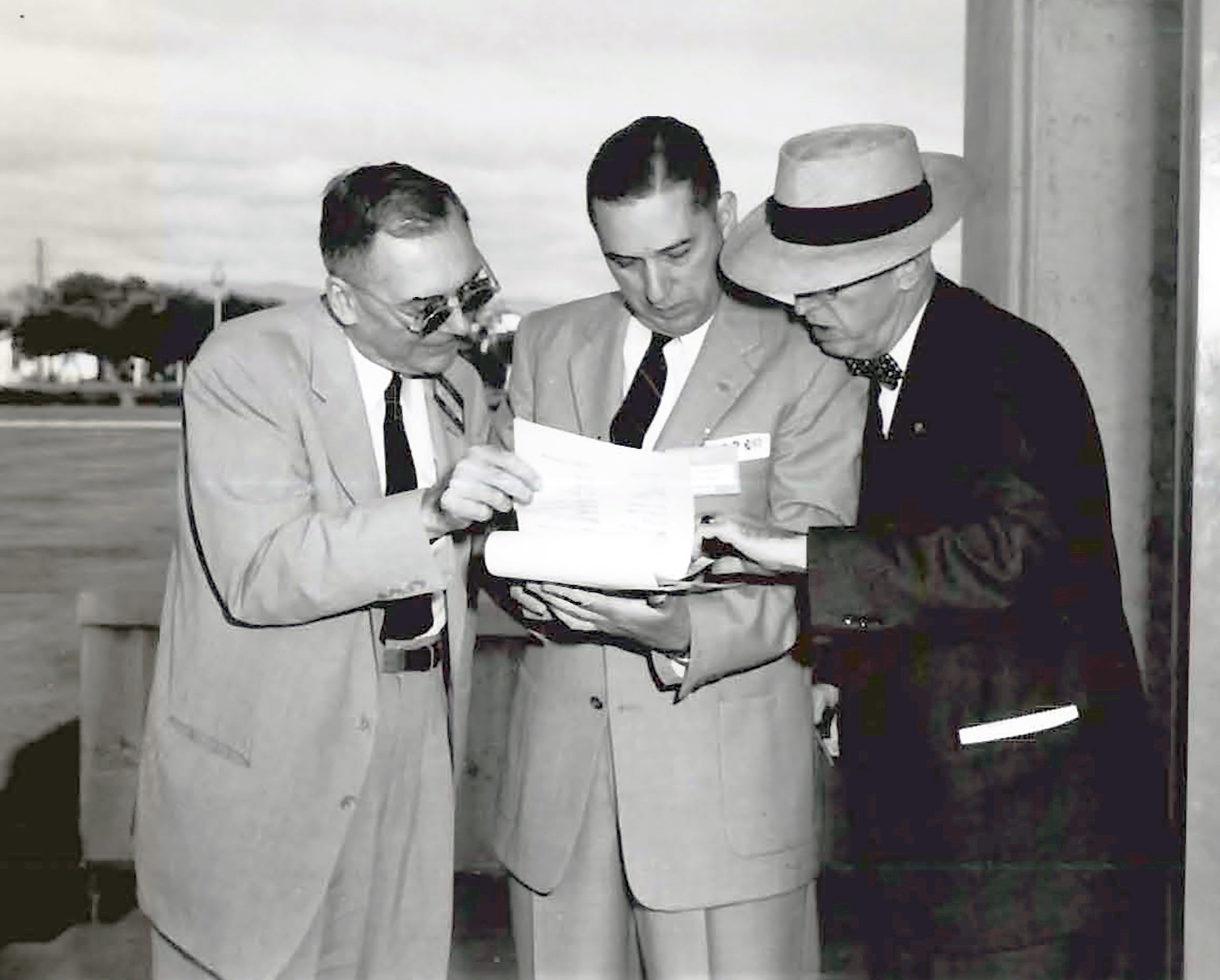 Three men reviewing document.