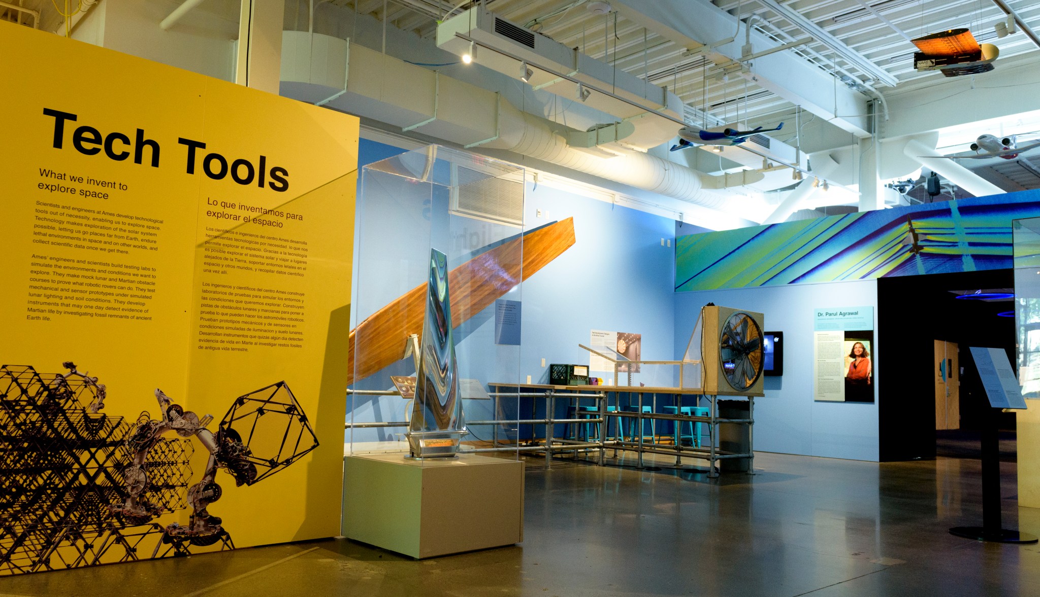 A wide shot of the new NASA Ames Visitor Center at Chabot Space & Science Center. At left, an exhibit description "Tech Tools" with a description of engineering work at Ames. At center and right, several historic pieces of Ames equipment are on display.