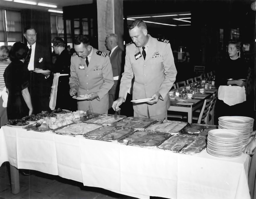 Men in uniform at buffet table.