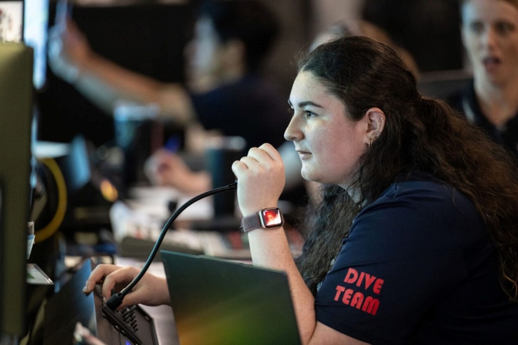 A Micro-g NExT participant wearing a 'Dive Team' shirt speaks into a microphone in a control room.